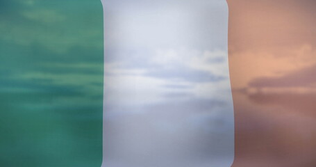 Billowing transparent tricolor flag showing green white orange stripes outdoors with cloudy sky