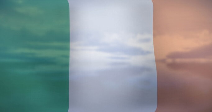 Fototapeta Billowing transparent tricolor flag showing green white orange stripes outdoors with cloudy sky