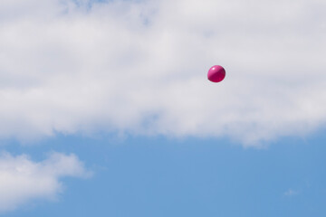 Pink balloon floating in blue sky