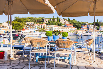 A tranquil outdoor cafe terrace with tables and chairs, offering a panoramic view of a sunny...