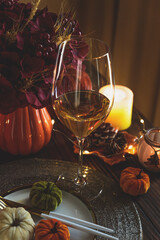 Thanksgiving table setting with decorative pumpkins, candles and string lights on dark wooden table