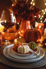 Autumnal table setting with decorative pumpkins, candles and string lights.