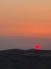 red heart in the sky. Crimson Sun Setting Behind Rock Formations. Red sun. 