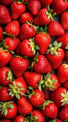 Fresh, vibrant strawberries fill the frame, showcasing their rich red hue and tiny green leaves against a dark background.