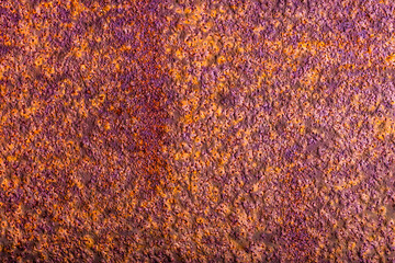 Metal surface with a thick layer of rust, exhibiting a predominantly purple hue with hints of...