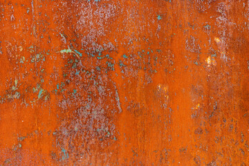 Texture of Rusty orange metal surface with remnants of blue paint, showing signs of corrosion and wear.