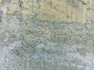 A close-up shows a damaged concrete wall texture where the outer layer has crumbled away, revealing the aggregate underneath. This suggests a construction defect or significant weathering of the