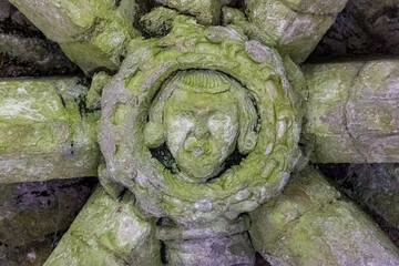 Close-up of a weathered medieval grotesque face carved in stone at Brougham Castle