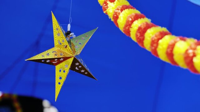 Golden star and garland hanging on blue background representing traditional indian festive decorations