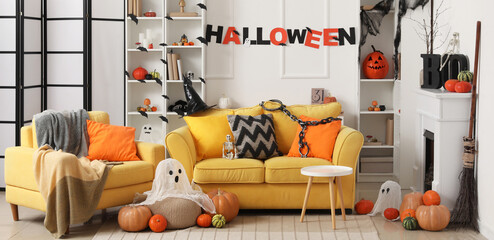 Interior of festive living room with yellow sofa, fireplace and different Halloween decorations