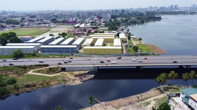 Expansive aerial view captures modular buildings, highway, water, and cityscape under a cloudy sky ivory coast