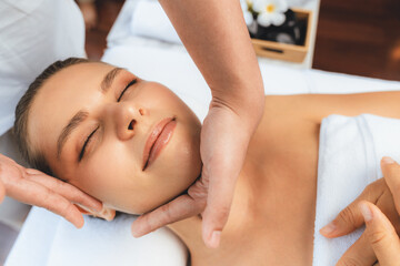Caucasian woman enjoying relaxing anti-stress head massage and pampering facial beauty skin recreation leisure in dayspa modern light ambient at luxury resort or hotel spa salon. Quiescent