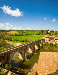 Naklejka premium Ancient bridge over a river in a Tuscan valley