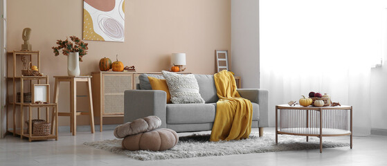 Interior of cozy living room with autumn decor, sofa and table