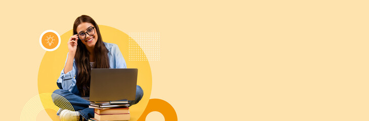 A student sits cross-legged on the floor, using a laptop while surrounded by books.