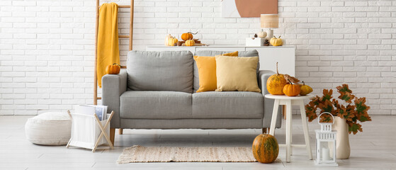 Interior of light living room with autumn decor, sofa and table
