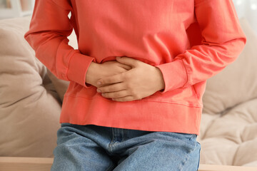 Young woman suffering from stomach ache at home, closeup
