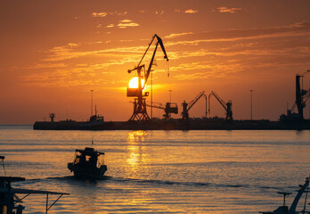 Industrial port of Heraklion with cranes and boat at sunrise in Heraklion Greece