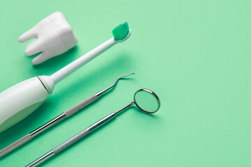 Electric toothbrush, dental tools and tooth model on green background. World Dentist Day