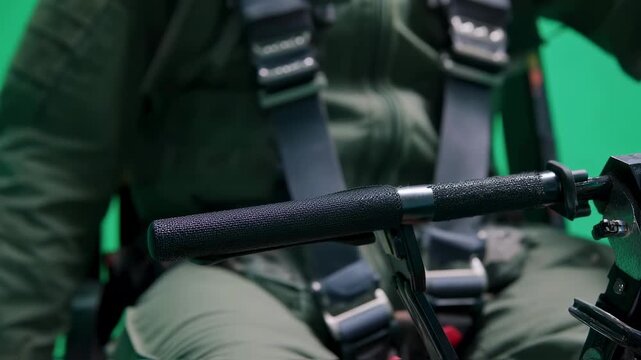 Detailed view of pilot gripping and pulling ejection seat handle against green screen emphasizing fastresponse lifesaving technology in aviation safety drills.