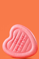 Swimming mattress in shape of heart on orange background