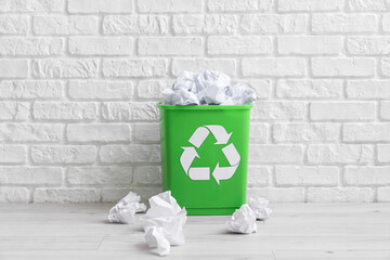 Recycling bin with paper near white brick wall. Recycle concept