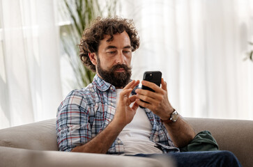 Man on couch using smartphone indoors