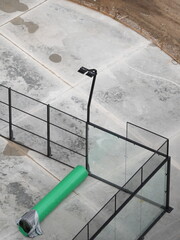 Construction of outdoor sports ground with metal fence, lamp post and green roll of artificial...