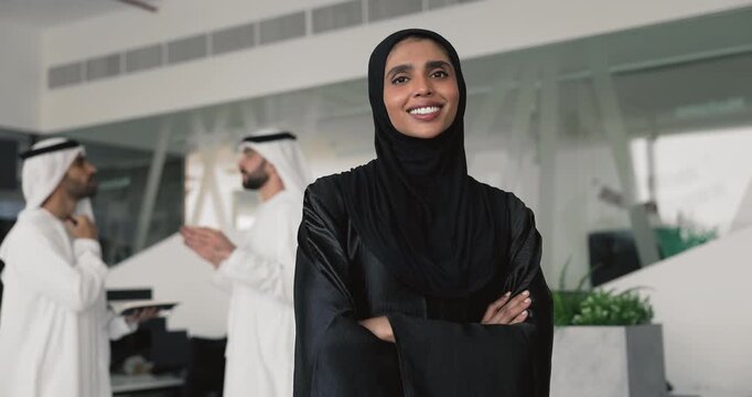 Happy confident young Muslim businesswoman standing in office