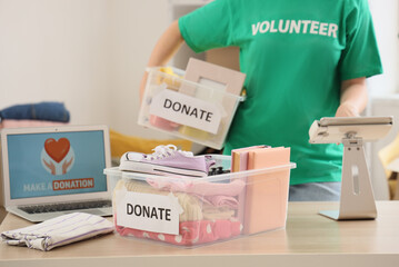 Female volunteer with container for donation using tablet computer in center