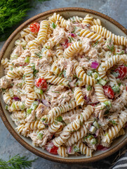 Tuna pasta salad with mayonnaise dressing, tomatoes, celery, red onion and dill in a bowl