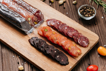 Assorted gourmet sausages sliced and vacuum packed on rustic wooden background with spices