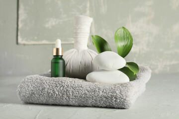 Composition with spa stones, green leaves, herbal bag and bottle of cosmetic products on green...