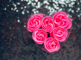 A heart-shaped container filled with pink roses. The roses are arranged in a way that they look...