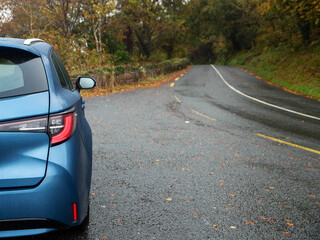 Blue car parked off small narrow asphalt road in a country side. Nobody. Travel and tourism. Taking...