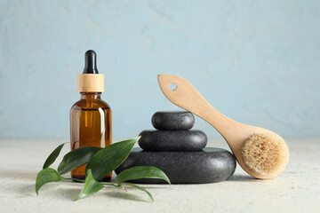 Composition with spa stones, green twig and bottle of cosmetic product on white table near blue...