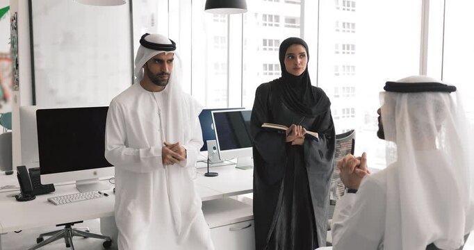 Three male and female Arabic businesspeople discussing work strategy