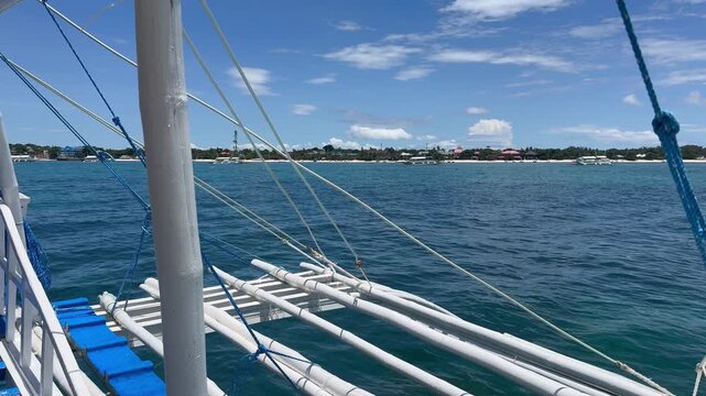 A traditional Philippine banca boat glides over turquoise waters toward Malapascua Island, a diving paradise in Southeast Asia known for its serene tropical beauty.