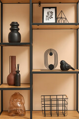 Black shelf unit with stylish decor near beige wall