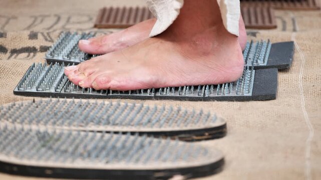 Fakir placing foot on nail board during spiritual practice in India