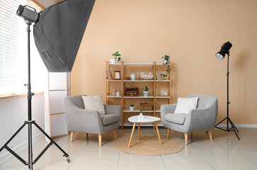 Photo shoot of living room with armchairs, shelf unit and folding screen in studio