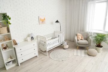 Interior of children's bedroom with crib, armchair and lamp