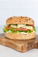 Burger or bagel with salmon, cream cheese and vegetable on white background. Healthy breakfast. Copy space.