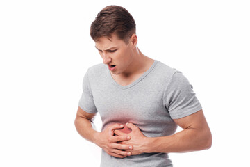 Unhappy young european male suffering from stomach pain, pressing hand to body, isolated on white...