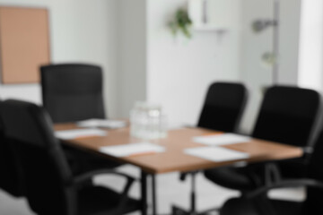Blurred view of table with water bottles and paper sheets prepared for business meeting in...