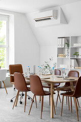 Interior of conference hall with table, shelf unit and plants