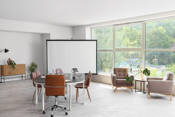 Interior of conference hall with tables, armchairs and projector screen