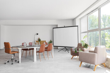 Interior of conference hall with desk, armchairs and projector screen