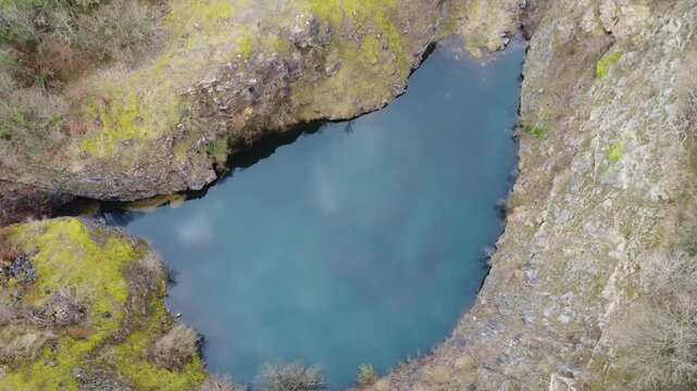 Ashover, North East Derbyshire, England - February 25 2024: Drone footage captures the industrial landscape of Fall Hill Quarry, showcasing its rugged cliffs and tranquil pool.