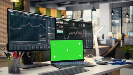 Fototapeta premium Stock market metrics diagrams displayed on green screen laptop in prop firm office. Workstation in forex company workspace with live financial data visible on mockup notebook